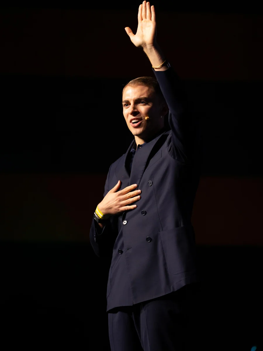 Emanuel Lacitignola sul palco con una mano alzata, rivolto alla sala