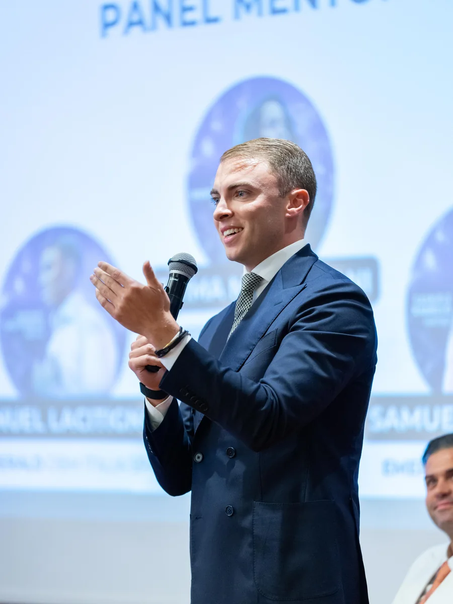 Emanuel Lacitignola durante un panel, con i relatori proiettati alle spalle